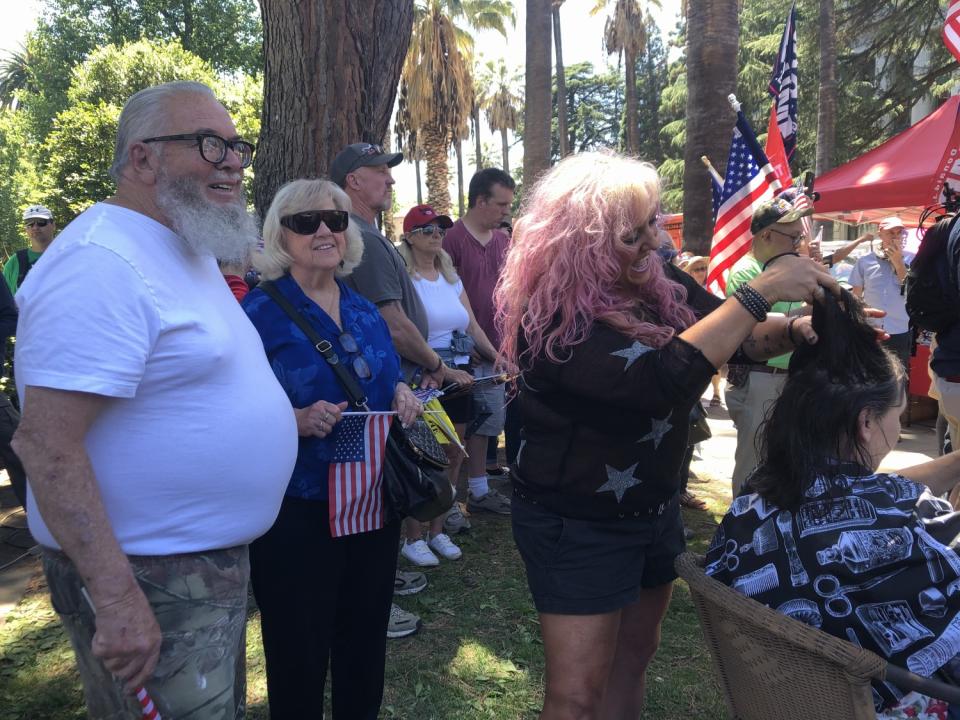 John DeBow and wife Ruth watch daughter Sheri gives free haircuts at a Sacramento rally.