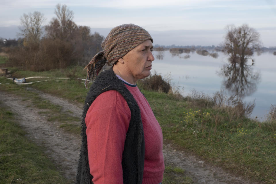 Tetyana Samoilenko, 51, walks near the flooded area in the village of Demydiv, about 40 kilometers (24 miles) north of Kyiv, Ukraine, Tuesday, Nov. 2, 2022. "I feel depressed — there's water all around and under my house," said Demydiv resident Tatiana Samoilenko. "I don't see much changing in the future." (AP Photo/Andrew Kravchenko)