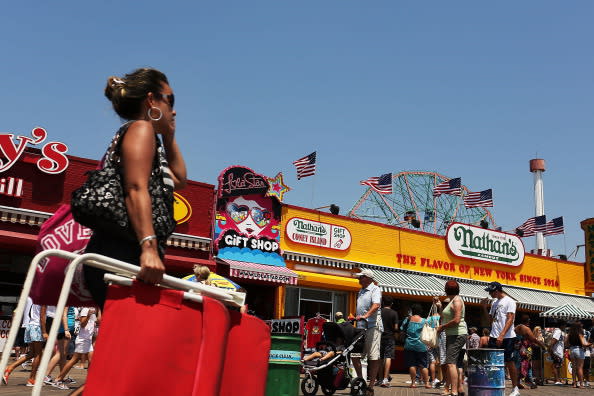 People walk along the boardwalk in Coney Island on July 12, 2012 in the Brooklyn borough of New York City. Coney Island has until recently been viewed as a seedy and dilapidating seaside park, however, it is going through a gradual transition which many compare to the renovation of Times Square. In order to accommodate more shops and residential buildings, the Michael Bloomberg administration rezoned Coney Island in 2009. The city also bought seven acres of prime Coney Island real estate promising approximately $150 million in infrastructure upgrades in the area. A recent study found that Coney Island's Luna Park had 640,000 visitors in 2011, the most since Steeplechase Park closed in 1964. (Photo by Spencer Platt/Getty Images)