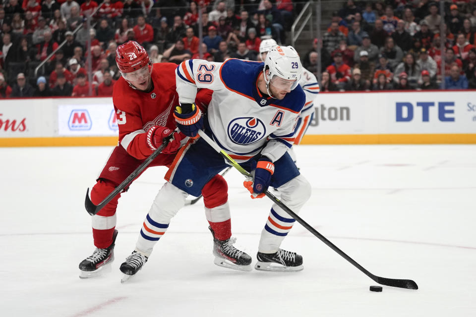 Edmonton Oilers center Leon Draisaitl (29) protects the puck from Detroit Red Wings left wing Lucas Raymond (23) in overtime during an NHL hockey game Thursday, Jan. 11, 2024, in Detroit. (AP Photo/Paul Sancya)