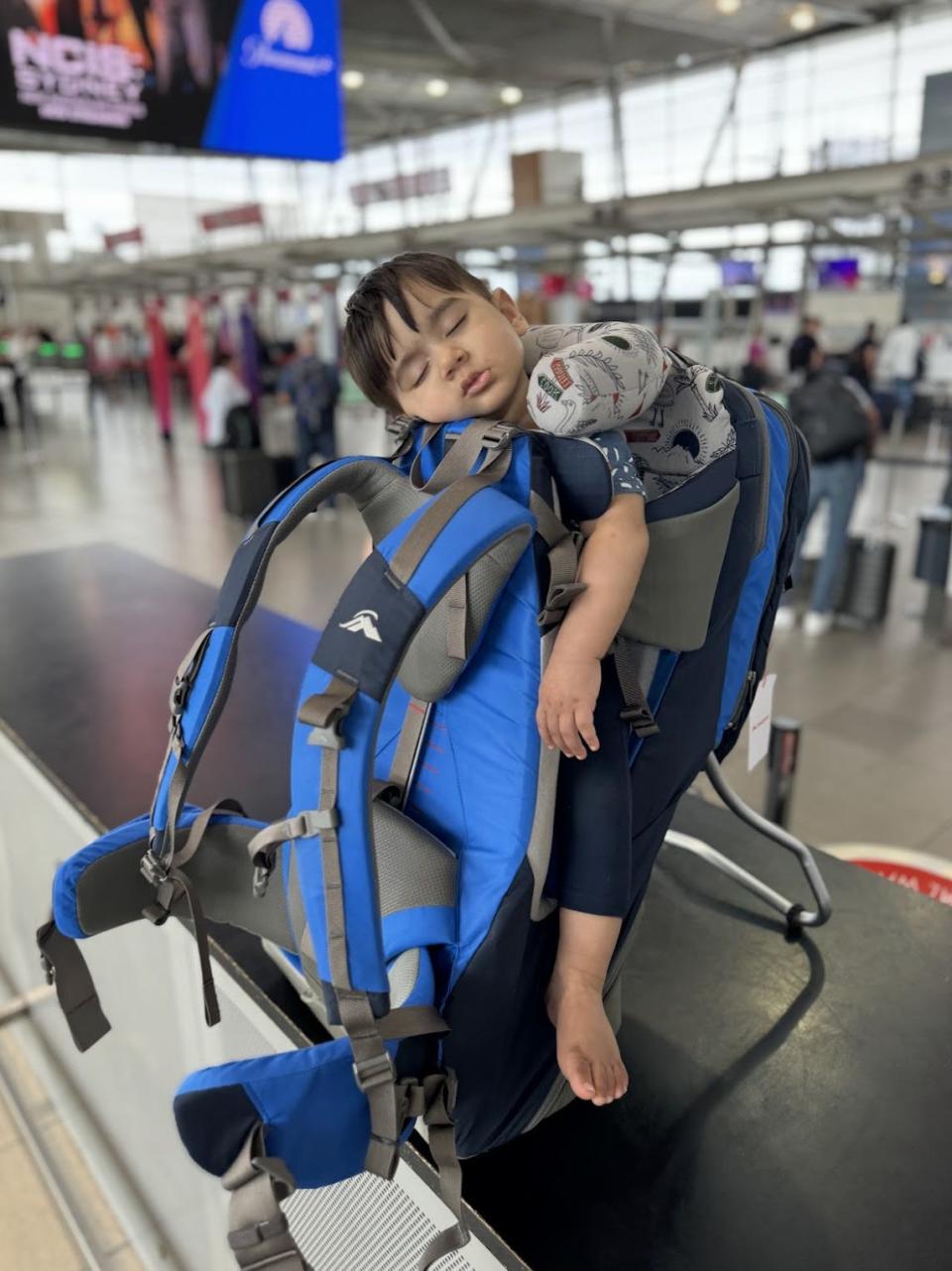 A baby in a carrier sleeping in the airport.