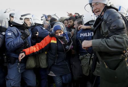 A Syrian refugee woman walks through a Greek police cordon whille trying to reach a narrow border crossing into Macedonia near to the Greek village of Idomeni December 4, 2015. REUTERS/Yannis Behrakis