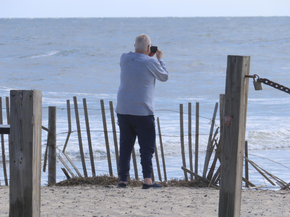 A beachgoer takes photos of the ocean horizon on Thursday, April 25, 2024 in Long Beach Township, N.J. Eight Jersey Shore towns, including Long Beach, are trying to convince New Jersey utility regulators that wind turbines planned for less than 9 miles off the town's coast will scare away visitors, costing the area jobs and economic development. The wind power industry rejects those claims, and says turbines can coexist with tourism and fishing. (AP Photo/Wayne Parry)