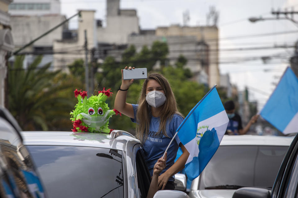 Una manifestante sale de su auto el jueves 18 de junio de 2020 durante una protesta para exigirle al presidente Alejandro Giammattei que ponga fin a la cuarentena con la que se pretende impedir la propagación del coronavirus, en Ciudad de Guatemala . (AP Foto/Moisés Castillo)