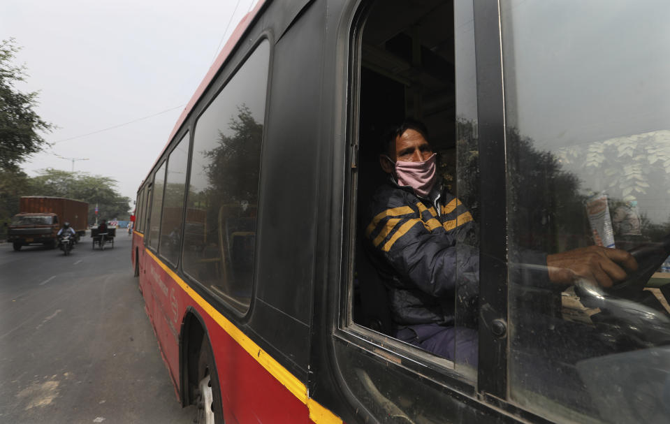 Delhi Transport Corporation bus driver Surinder Singh, 47, wearing a face mask as precaution against coronavirus and pollution drives in New Delhi, India, Wednesday, Nov. 25, 2020. India is grappling with two public health emergencies: critically polluted air and the pandemic. Nowhere is this dual threat more pronounced than in the Indian capital New Delhi, where the spike in winter pollution levels has coincided with a surge of COVID-19 cases. (AP Photo/Manish Swarup)