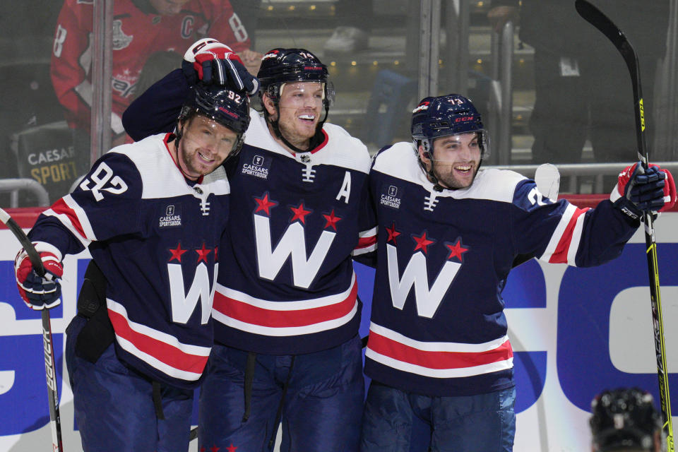 Washington Capitals center Evgeny Kuznetsov (92), defenseman John Carlson (74) and left wing Conor Sheary (73) celebrate a goal during the third period of an NHL hockey game against the Vancouver Canucks, Monday, Oct. 17, 2022, in Washington. (AP Photo/Jess Rapfogel)