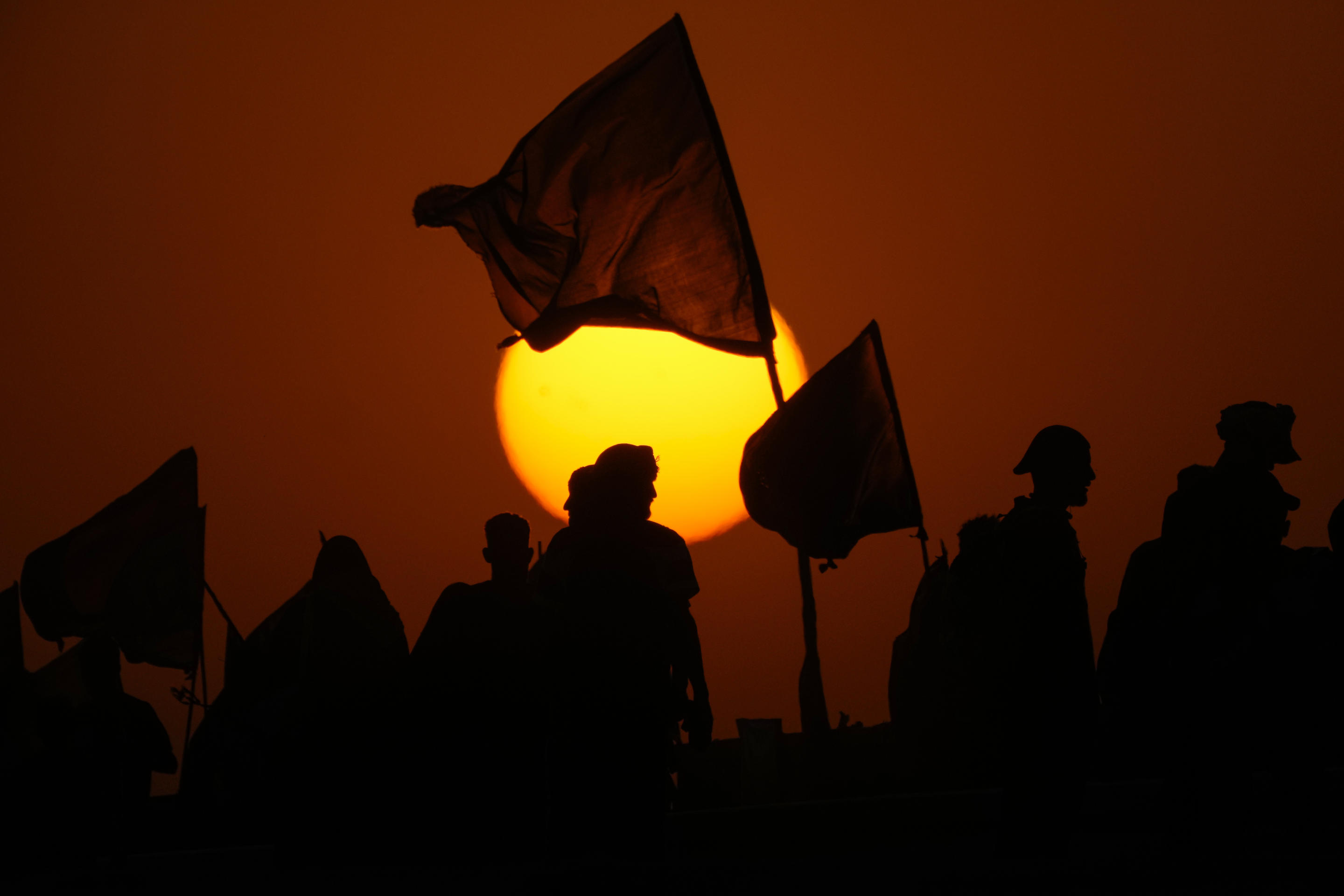 The sun sets as Shiite pilgrims make their way to Karbala for the Arba'een festival in Babil, Iraq, Monday, Aug. 19, 2024. (Hadi Mizban/AP)