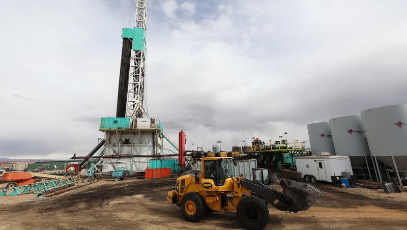 A worker operates a loader as a rig drills a well near Roosevelt, Utah, on March 13, 2022.