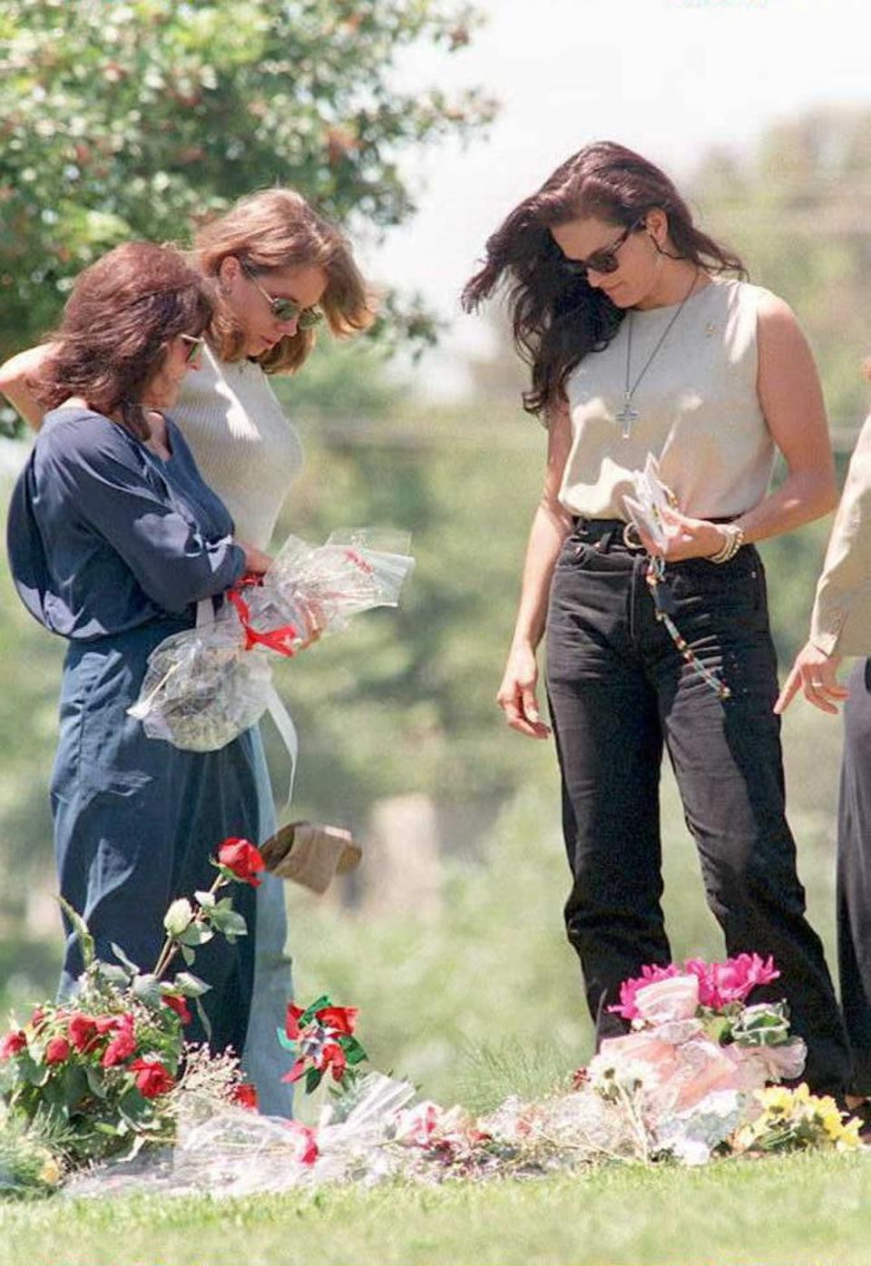 Nicole Brown's mother Juditha (L), and sisters Denise (R) and Tanya (C) stand next to her grave in Lake Forest, California, on the one-year anniversary of her murder in 1995 (AFP via Getty Images)
