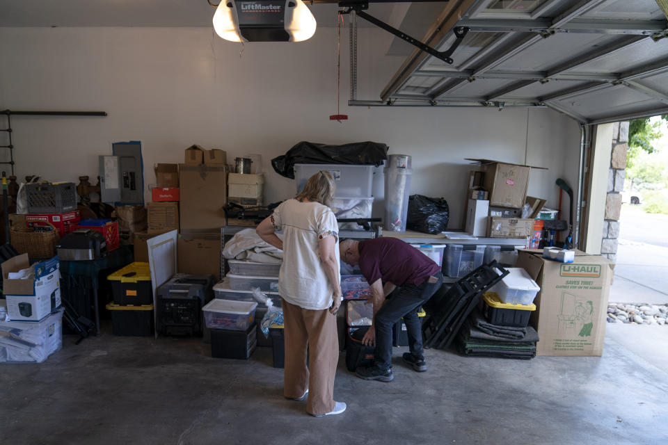Lonnie Phillips, right, and his wife, Sandy, sift through their belongings stored at a friend’s garage in Lone Tree, Colo., Monday, Sept. 4, 2023. Since Sandy’s daughter, Jessica Ghawi, was killed in a 2012 mass shooting in a movie theater, the pace of other mass killings only intensified. Instead of tighter gun laws, some states loosened them. Exhausted, disgusted and impoverished, the Phillipses recently moved to Mexico. (AP Photo/David Goldman)