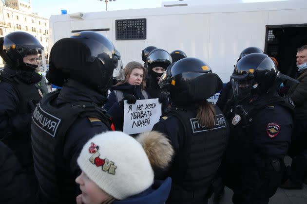 A Russian police officer detain a woman holding the poster reads: 