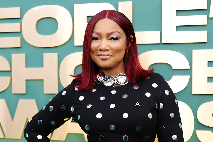 Garcelle Beauvais smiles in a black dress with silver polka dots.