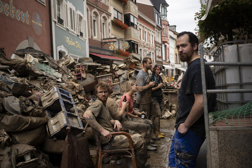 People take a break from cleaning the debris from the flood disaster in Bad Neuenahr-Ahrweiler, Germany, Monday July 19, 2021. More than 180 people died when heavy rainfall turned tiny streams into raging torrents across parts of western Germany and Belgium, and officials put the death toll in Ahrweiler county alone at 110. (AP Photo/Bram Janssen)