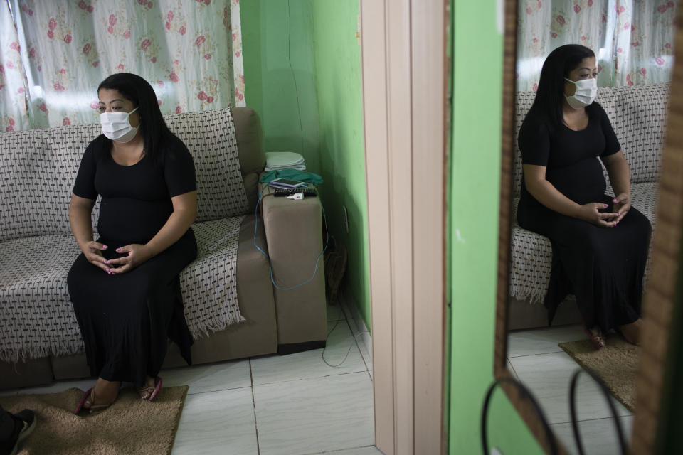 Nurse Lidiane Melo sits during an interview with The Associated Press at her home in Rio de Janeiro, Brazil, Wednesday, April 14, 2021. In the early days of the pandemic, as sufferers were calling out for comfort that she was too busy to provide, Melo filled two rubber gloves with warm water, knotted them shut, and sandwiched them around a patient's hand, to re-create a loving clasp. Some have christened the practice the "hand of God," and it is now the searing image of a nation roiled by a medical emergency with no end in sight. (AP Photo/Silvia Izquierdo)