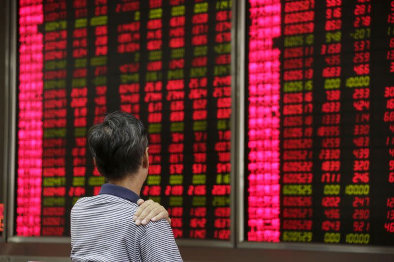 FILE PHOTO: An investor looks at an electronic board at a brokerage house in Beijing