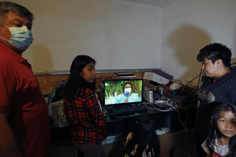 Jose Juan Serralde, left, and his daughters gather around a computer playing a video featuring his late mother, Esther Serralde Galicia, inside their home in San Gregorio Atlapulco, Xochimilco, Mexico City, Wednesday, July 29, 2020. After Serralde's parents died from COVID-19 in May, he, his wife, and their four daughters spent weeks quarantined in their home while some had mild cases of COVID-19 before recovering. (AP Photo/Rebecca Blackwell)