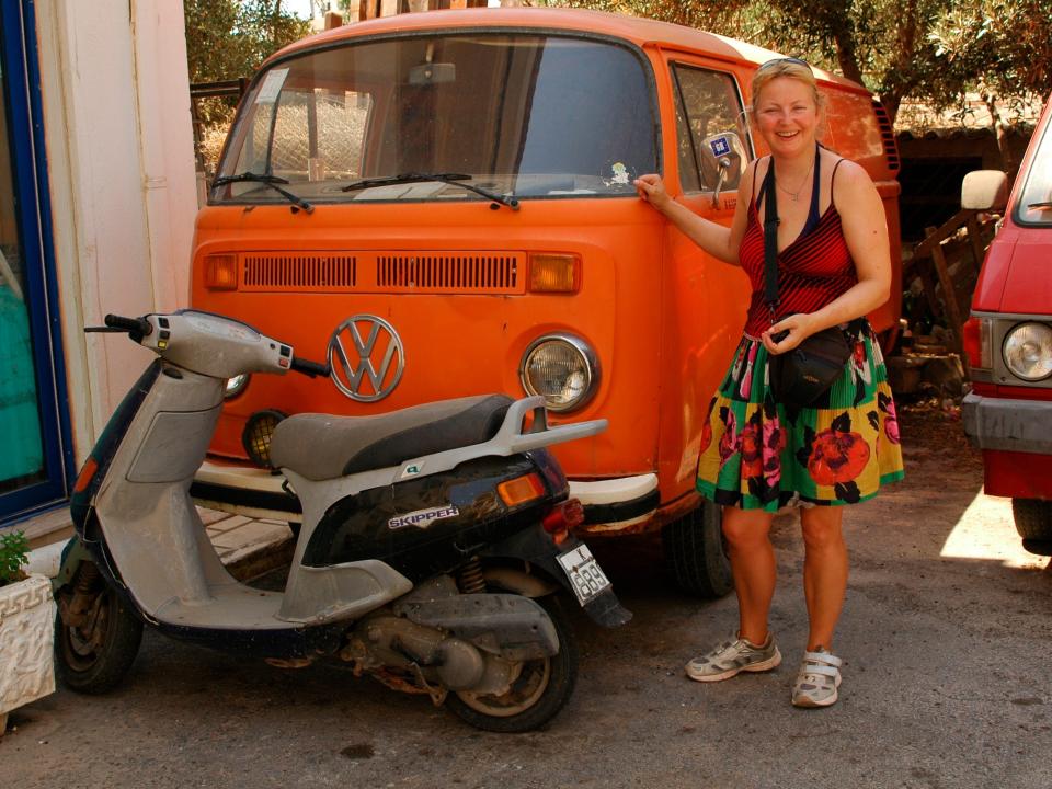 A woman posing next to an orange VS bus van.