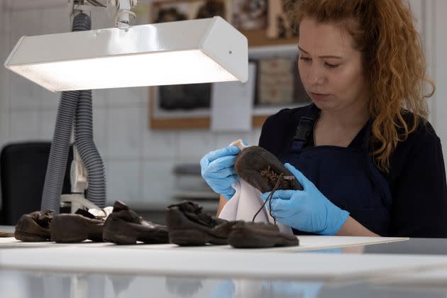 A worker rubs away dust on a shoe that belonged to a child victim of the former Nazi German death camp Auschwitz-Birkenau.