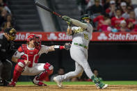 Oakland Athletics' Seth Brown follows through on a two-run home in front of Los Angeles Angels catcher Chad Wallach and home plate umpire Larry Vanover during the fifth inning of a baseball game in Anaheim, Calif., Friday, May 20, 2022. (AP Photo/Alex Gallardo)
