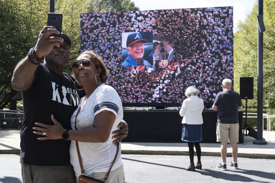 Kevin and Ursula Jones take a photo together in front of a video screen while attending the celebration for President Jimmy Carter's 99th birthday held at The Carter Center in Atlanta on Saturday, Sept. 30, 2023. (AP Photo/Ben Gray)