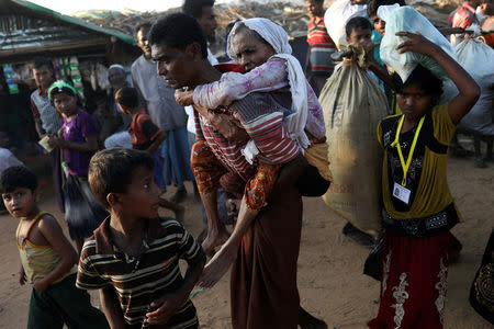 Rohingya refugee Suray Khatun, 70, is carried by her son Said-A-Lam, 38, as they enter Kutupalong refugee camp, near Cox's Bazar, Bangladesh a day after crossing the Myanmar border, November 20, 2017. REUTERS/Susana Vera