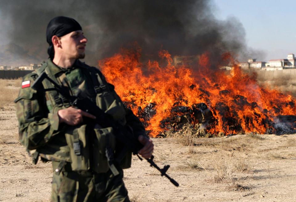 A Polish soldier stands guard in front of a pile of burning illegal narcotics in Afghanistan's Ghazni province in November 2008