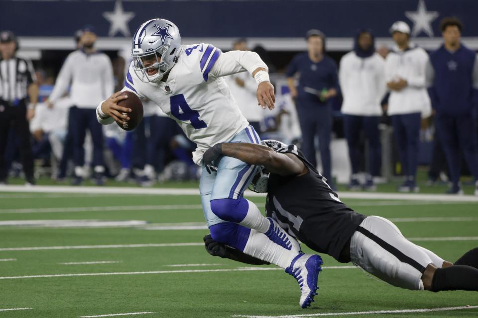 Dallas Cowboys quarterback Dak Prescott (4) is stopped as he runs the ball by Las Vegas Raiders defensive end Yannick Ngakoue, right, in the second half of an NFL football game in Arlington, Texas, Thursday, Nov. 25, 2021. (AP Photo/Michael Ainsworth)