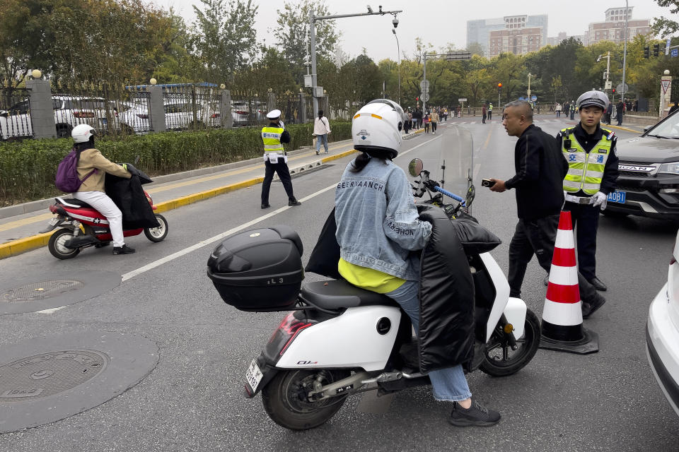 A motorist is stopped by policemen near a road where the convoy which is believed to be carrying the body of former Premier Li Keqiang heads to the Babaoshan Revolutionary Cemetery in Beijing Thursday, Nov. 2, 2023. Hundreds, possibly thousands, of people gathered near a state funeral home Thursday as former Premier Li Keqiang was being put to rest. (AP Photo/Andy Wong)