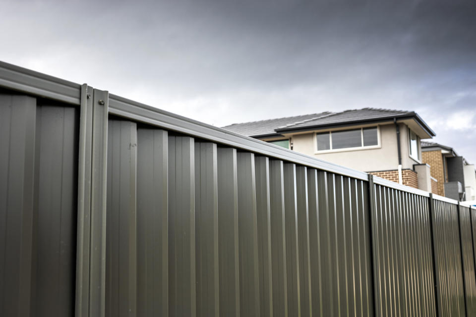 A metal boundary fence with a house behind it. 