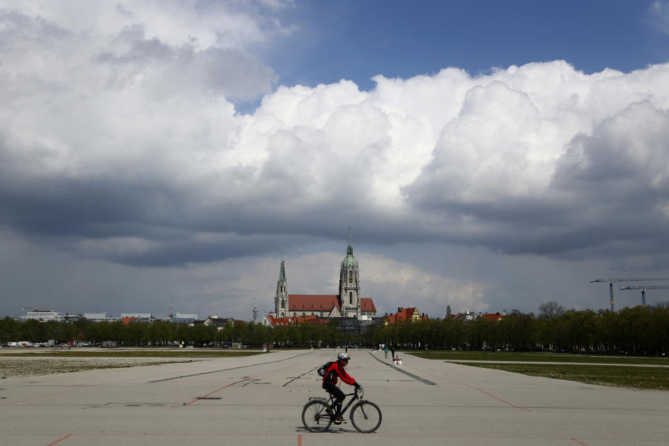 A cyclist crosses the 'Oktoberfest' beer festival area 'Theresienwiese' in front of the St. Pauls church in Munich, Germany, Monday, May 3, 2021. The world's largest beer festival 'Oktoberfest' was cancelled last year due to the coronavirus outbreak. (AP Photo/Matthias Schrader)