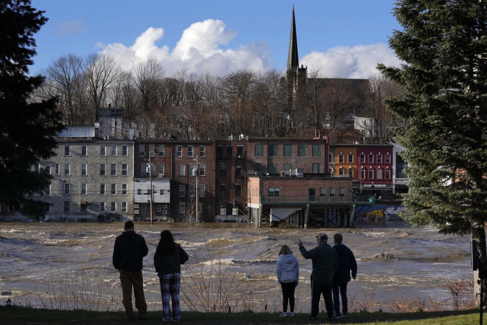Spectators watch the flooded Kennebec River flow through Augusta, Maine, Tuesday, Dec. 19, 2023. Waters continue to rise in the river following Monday's severe storm. (AP Photo/Robert F. Bukaty)