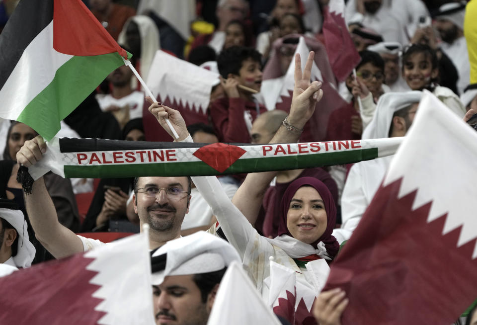 Fans wave the Palestinian flag and cheer prior the World Cup, group A soccer match between Qatar and Ecuador at the Al Bayt Stadium in Al Khor, Sunday, Nov. 20, 2022. (AP Photo/Ariel Schalit)