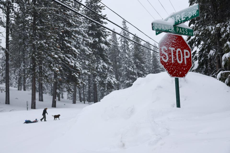 A person pulls kids on a sled with a dog walking ahead on Donner Pass Road during a powerful multiple day winter storm in the Sierra Nevada mountains on March 03, 2024 in Truckee, California.