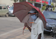 A man wearing a face shield as a precautionary measure against the coronavirus walks on a street in Hyderabad, India, Tuesday, Oct. 27, 2020. India reports 36,470 new coronavirus cases, the lowest in more than three months in a continuing downward trend. However, the overall tally neared 8 million, the second in the world behind the U.S. with over 8.7 million positive cases. (AP Photo/Mahesh Kumar A.)