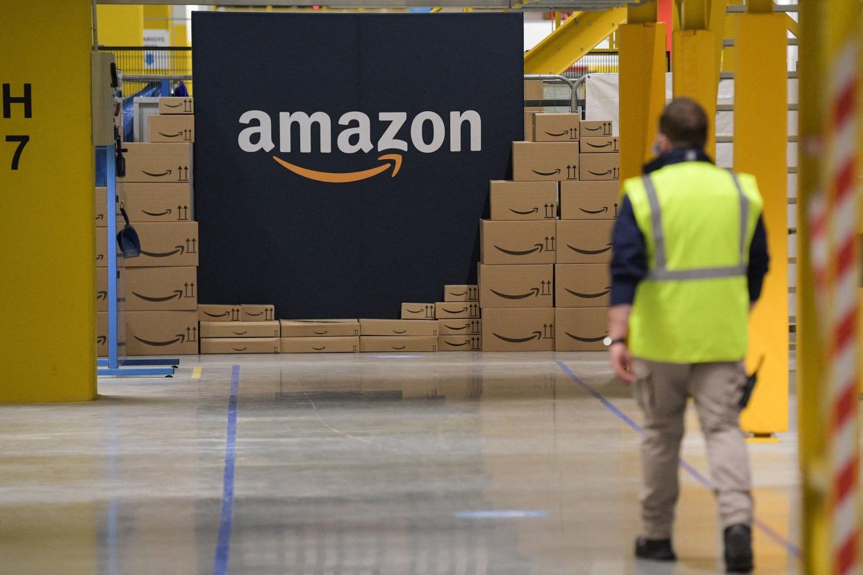 An Amazon employee passes by its logo on the opening day of the new distribution center in Augny, eastern France, on September 23, 2021