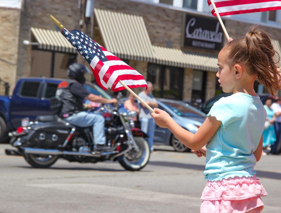 Bella Almeida, 6, waves a flag at members of the Rolling Thunder motorcycle crew during Fall River's Memorial Day parade, on South Main Street on Sunday, May 28, 2023.