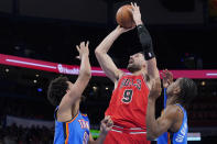 Chicago Bulls center Nikola Vucevic (9) shoots between Oklahoma City Thunder forward Jeremiah Robinson-Earl (50) and guard Shai Gilgeous-Alexander, right, in the second half of an NBA basketball game Monday, Jan. 24, 2022, in Oklahoma City. (AP Photo/Sue Ogrocki)