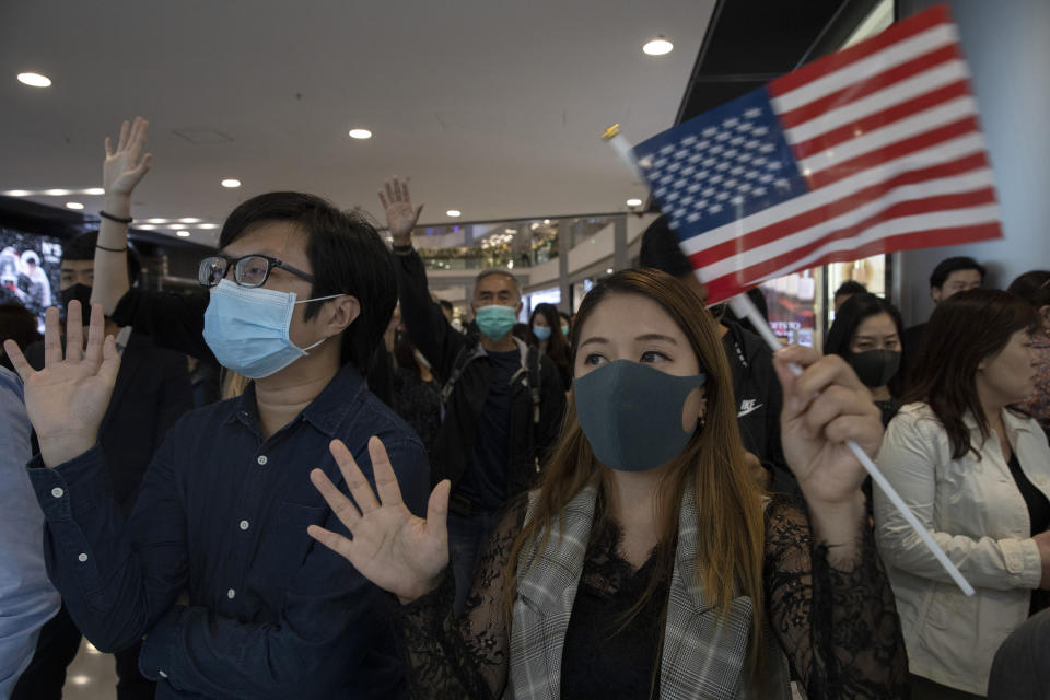 Hongkongers hold up their hands to represent their five demands and a United States flag as they chant "Pass the bill, save Hong Kong" at the IFC mall in Hong Kong Thursday, Nov. 21, 2019. Pressure ratcheted up on Hong Kong as the U.S. Congress approved legislation late Wednesday to sanction officials who carry out human rights abuses and require an annual review of the favorable trade status that Washington grants Hong Kong. Another bill bans export of tear gas and other non-lethal tools to Hong Kong, (AP Photo/Ng Han Guan)