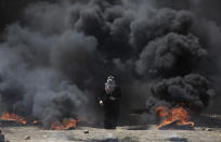 <p>A Palestinian woman walks through black smoke from burning tires during a protest on the Gaza Strip’s border with Israel, May 14, 2018. (Photo: Khalil Hamra/AP) </p>