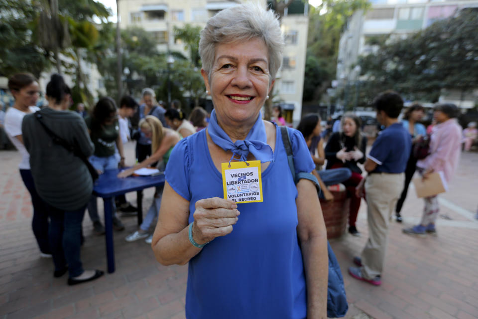 En esta foto del 19 de febrero de 2019, Alesia Santacroce muestra su credencial de voluntaria para ayudar a ingresar ayuda humanitaria al país durante una reunión de reclutamiento en una plaza de Caracas, Venezuela. (AP Foto/Fernando Llano)