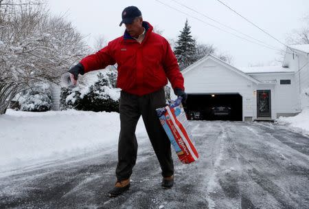 Peter Neal salts his driveway after snowplowing it clear in Bangor, Maine, U.S. December 30, 2016. REUTERS/Ashley L. Conti