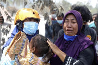 A woman weeps after her home was destroyed by the eruption of Mount Semeru in Lumajang district, East Java province, Indonesia, in Candi Puro village, Lumajang, East Java, Indonesia, Tuesday, Dec. 7, 2021. Indonesia's president on Tuesday visited areas devastated by a powerful volcanic eruption that killed a number of people and left thousands homeless, and vowed that communities would be quickly rebuilt. (AP Photo/Trisnadi)