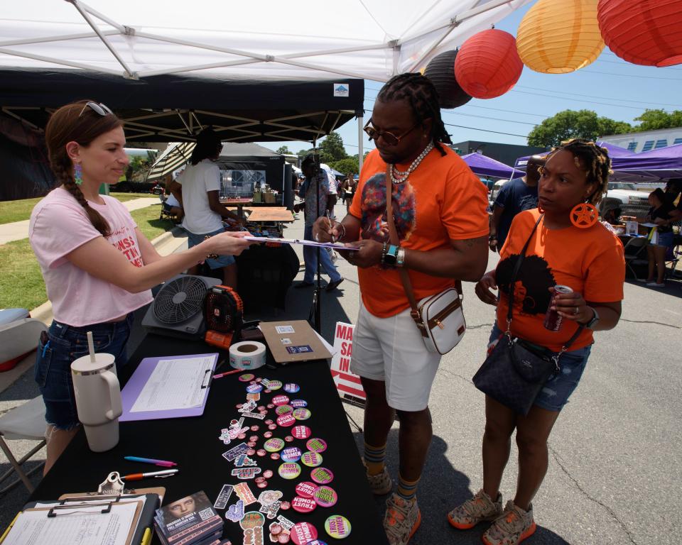 Dina Epstein, left, an OBGYN and physician leader with Arkansans for Limited Government, helps Chris Hayman, center, and Toni Hayman sign the petition for the Arkansas abortion amendment during the 15th Annual Juneteenth in Da Rock celebration at S. Arch Street in Little Rock, Ark., Saturday, June 15, 2024.