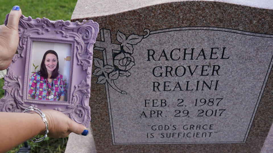 Sharon Grover holds up a photograph of her daughter, Rachael, over the gravesite at Fairview Cemetery, Tuesday, Sept. 28, 2021, in Mesopotamia, Ohio. Grover believes her daughter started using prescription painkillers around 2013 but missed any signs of her addiction as her daughter, the oldest of five children, remained distanced. (AP Photo/Tony Dejak)