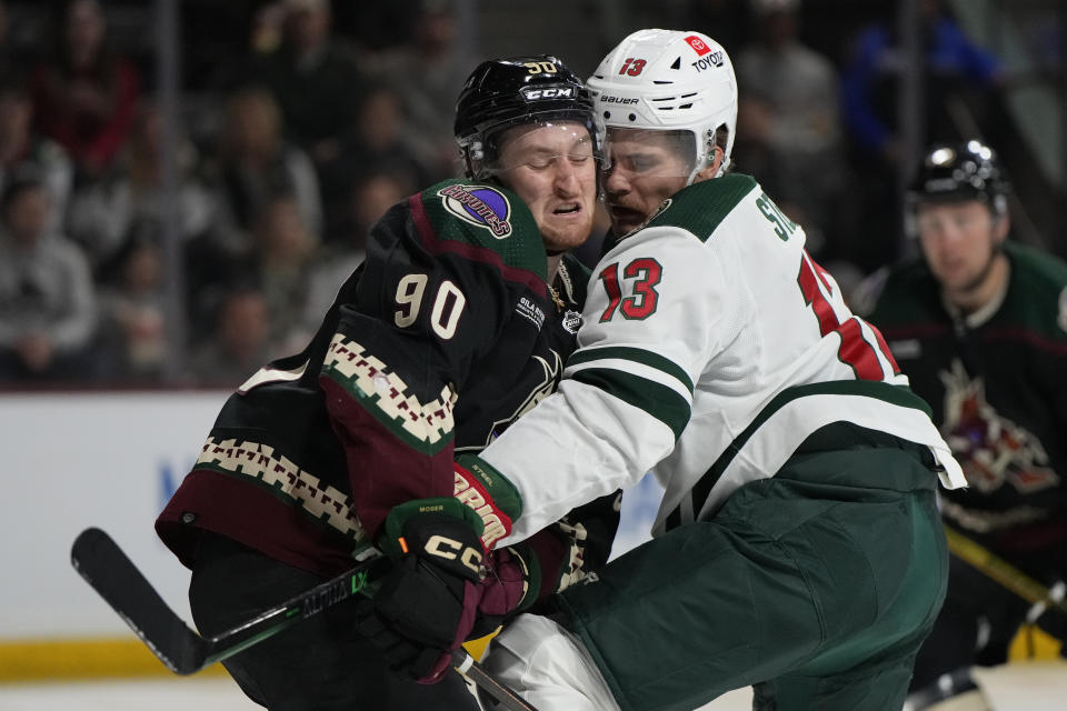 Arizona Coyotes defenseman J.J. Moser (90) and Minnesota Wild center Sam Steel collide in the second period during an NHL hockey game, Monday, Feb. 6, 2023, in Tempe, Ariz. (AP Photo/Rick Scuteri)