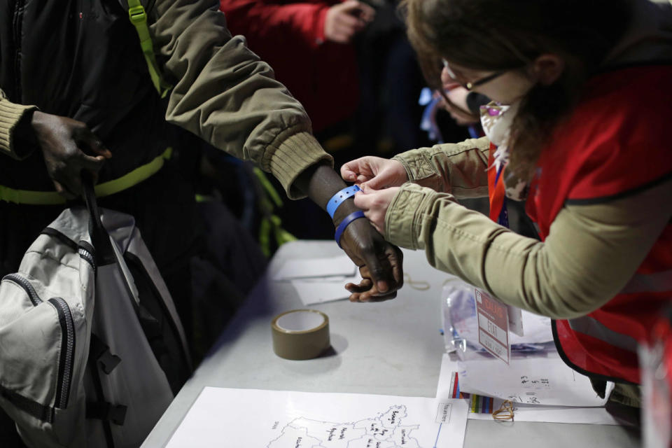 A resident is given a wristband before leaving for a refugee centre elsewhere in France. 