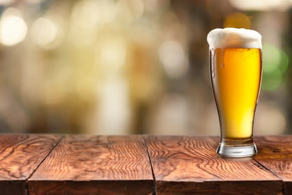 A pint of beer in a glass, on a table.