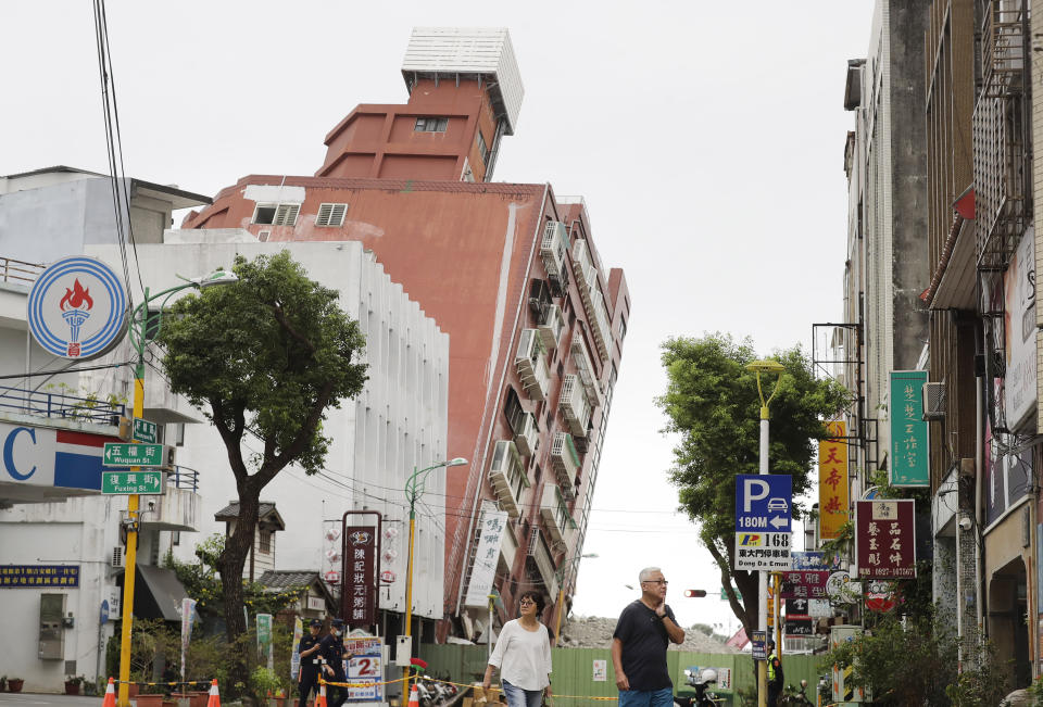 People walk past a building, seen partially collapsed, two days after a powerful earthquake struck the city, in Hualien City, eastern Taiwan, Friday, April 5, 2024. Rescuers searched Thursday for missing people and worked to reach hundreds stranded when Taiwan's strongest earthquake in 25 years sent boulders and mud tumbling down mountainsides, blocking roads. (AP Photo/Chiang Ying-ying)