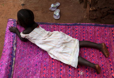 A three-year-old girl who was offered for international adoption without her family's knowledge lies on a mat at her grandmother's home in rural Uganda, April 14, 2015. REUTERS/Katy Migiro