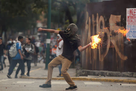 A demonstrator throws a molotov cocktail during clashes with riot police while rallying against Venezuela's President Nicolas Maduro in Caracas. REUTERS/Christian Veron